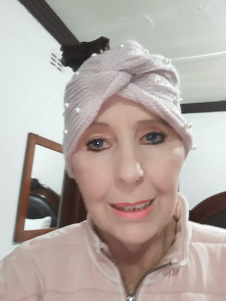 Woman with pink headwrap smiling indoors.